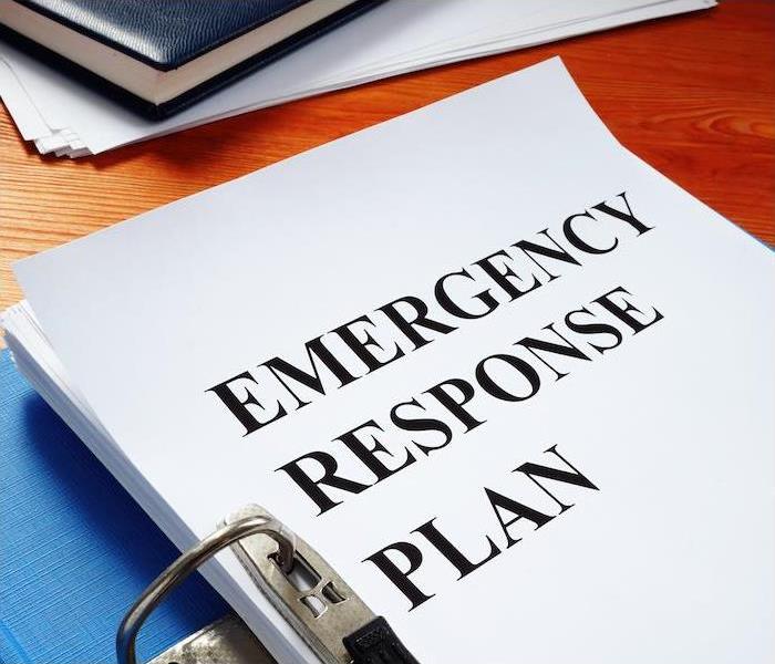 a book, paper and emergency response plan document sitting on wooden desk