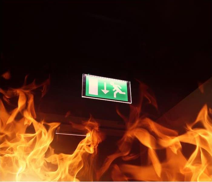 a green fire exit sign above flames from fire