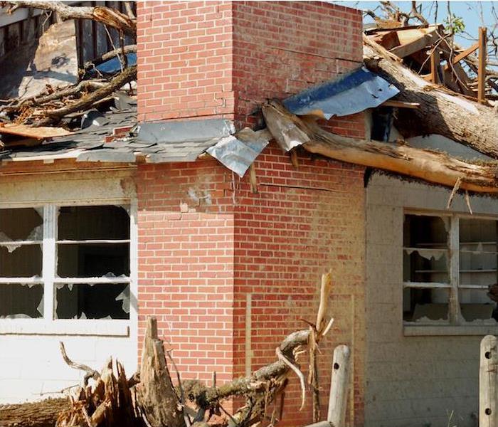 a red brick building showing signs of extensive storm damage and debris